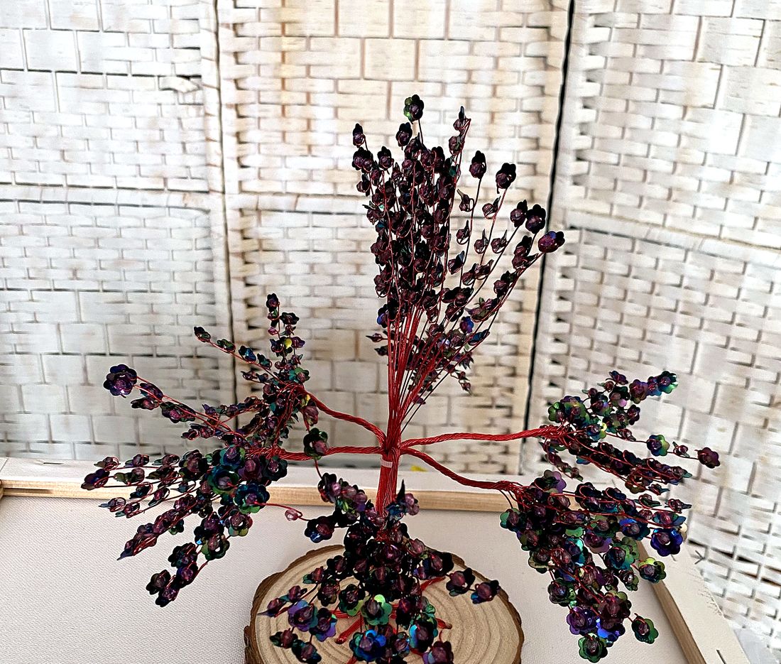 A memory tree part-way through being made, red wire branches with iridescent beads
